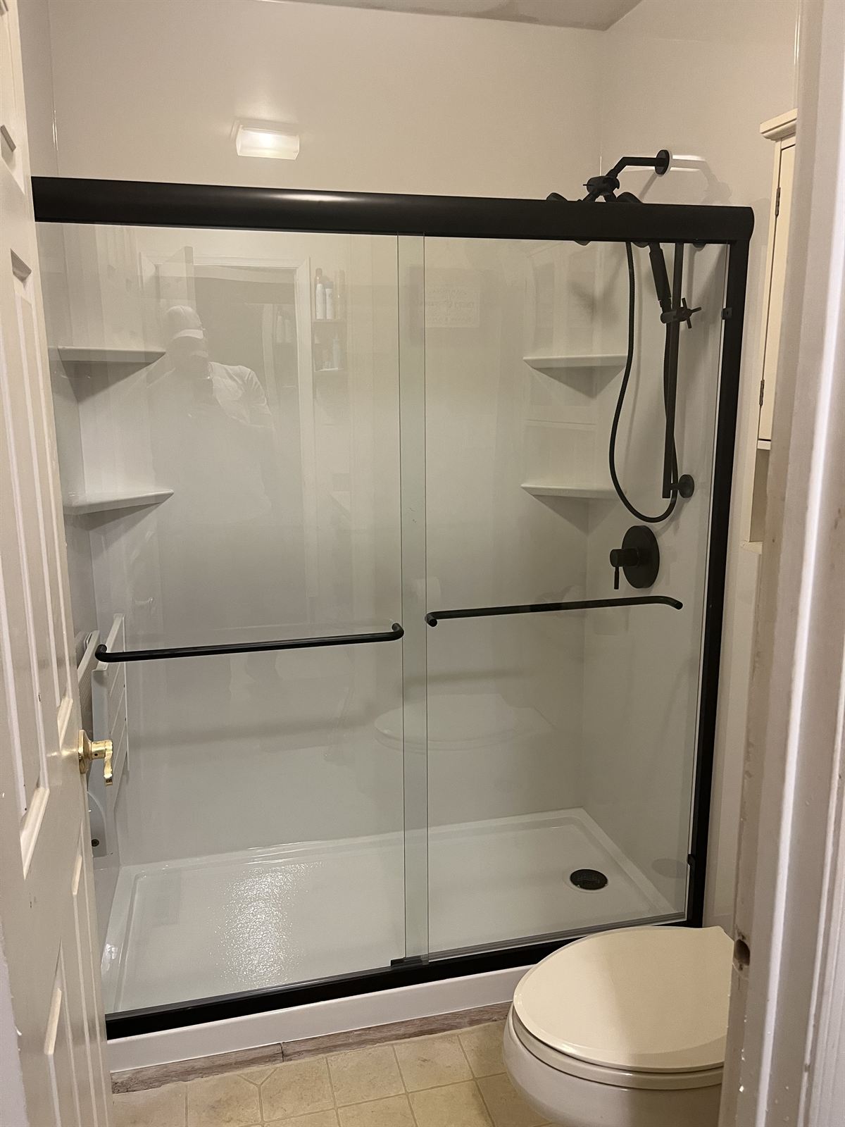 After: white shower with fold-down seat, grab bars and black hardware