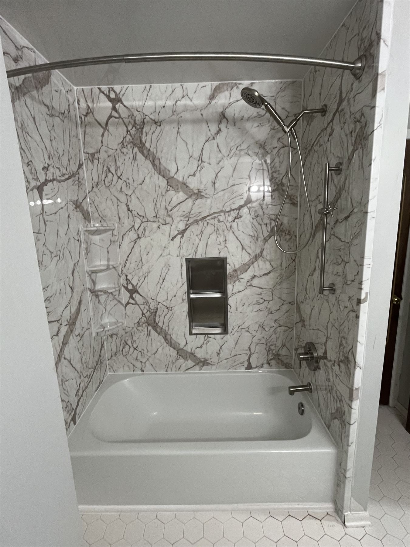 After: white marble look acrylic tub walls with a built-in stainless niche and new fixtures