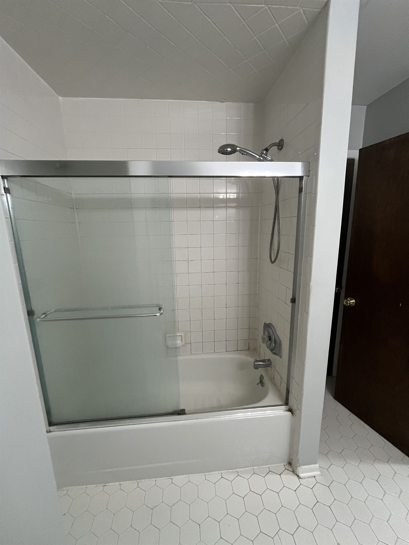 Before: dated white square tile tub surround with old framed sliding doors