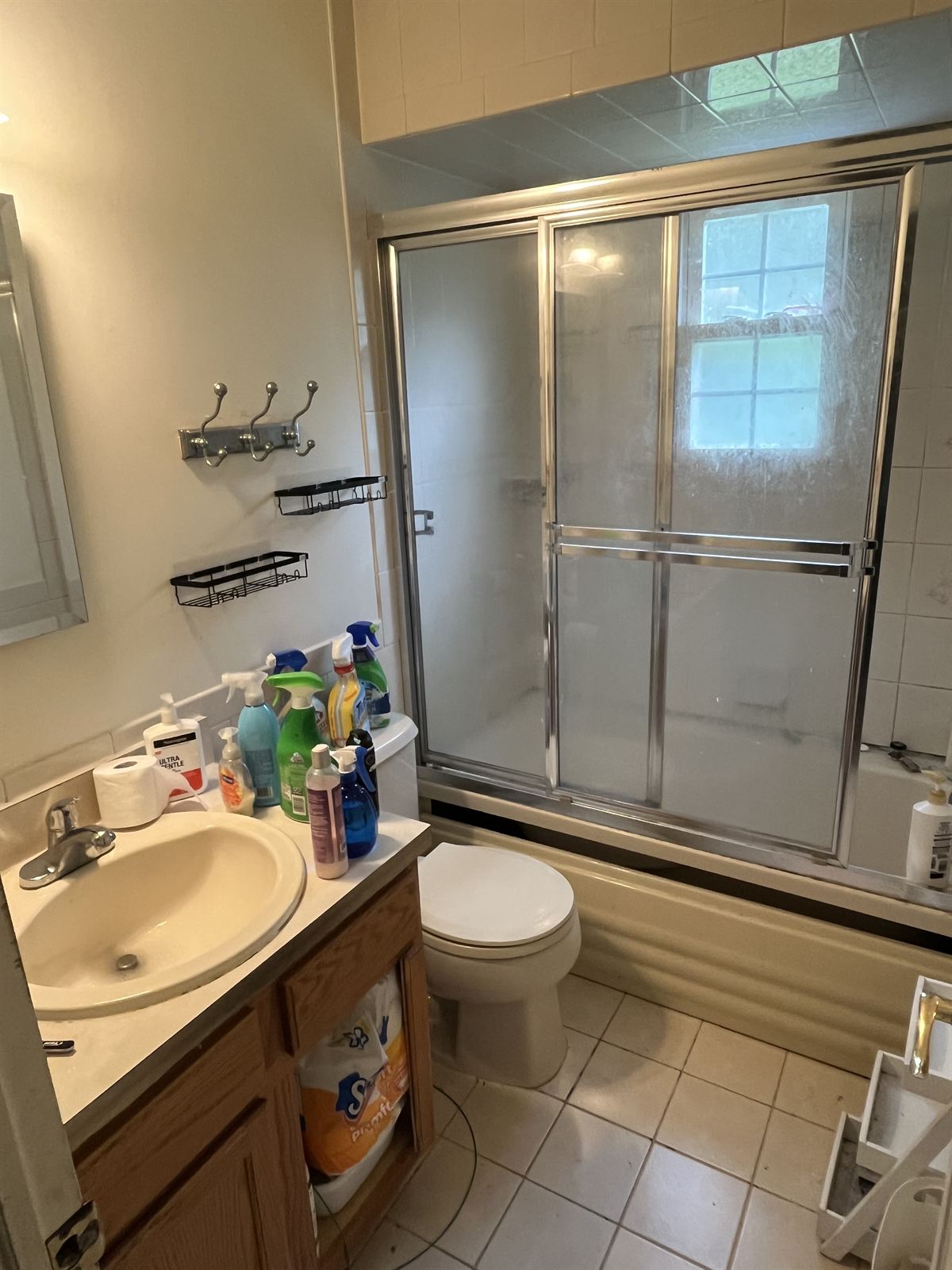Before: dated beige tile tub surround with an old framed frosted glass slider and oak vanity