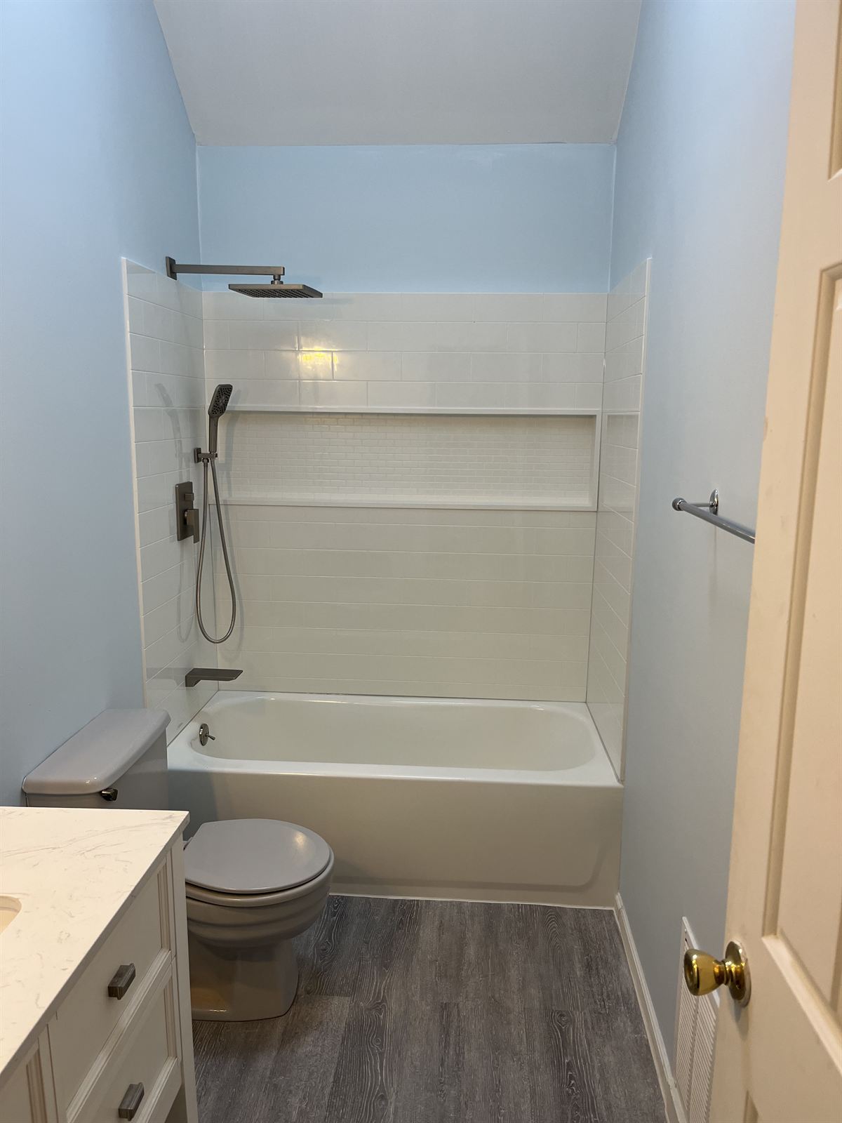 After: bright white fiberglass tub enclosure with a molded subway look, mosaic accent strip and rain style fixtures