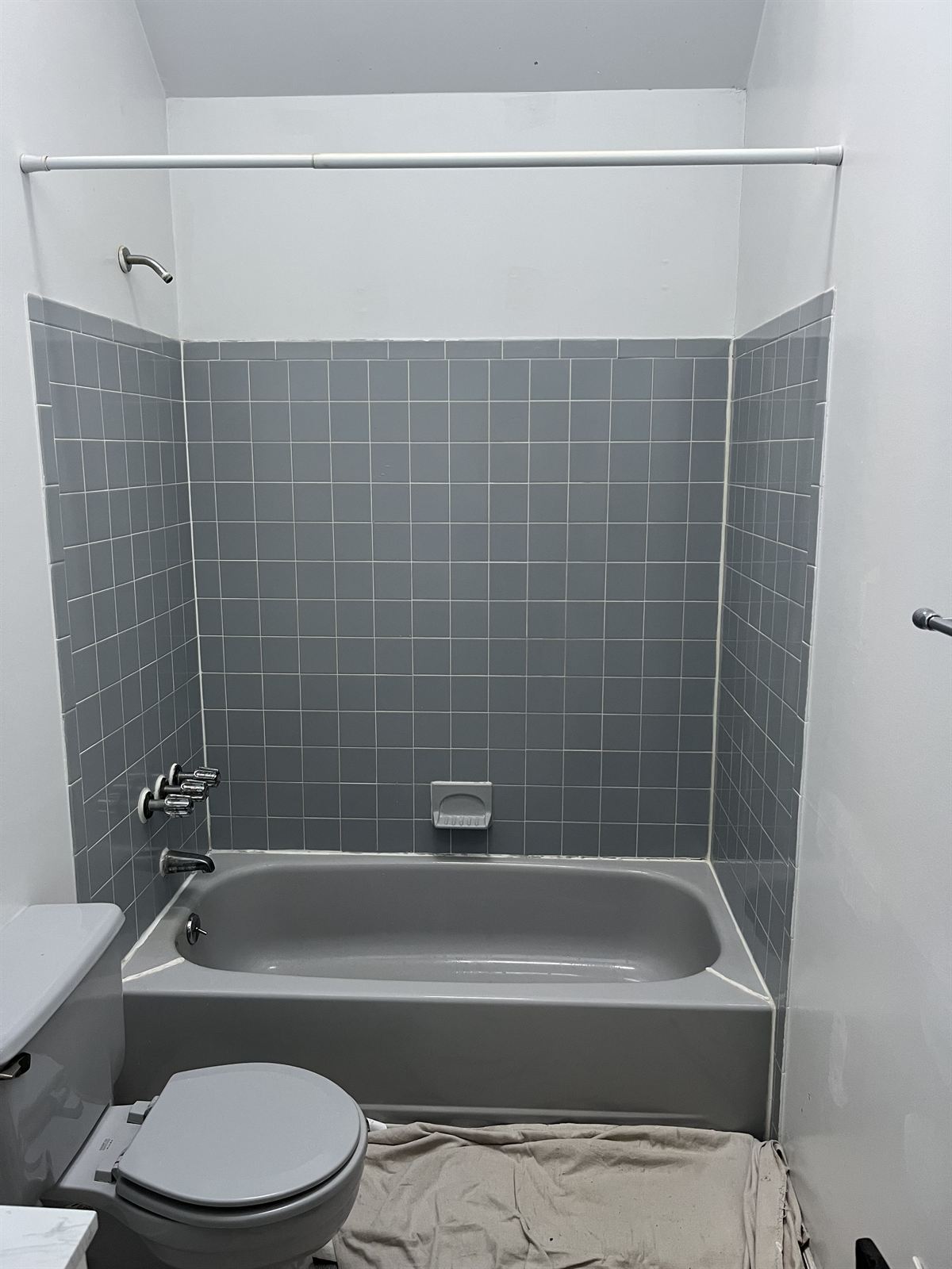 Before: dated gray square tile tub surround with old chrome hardware