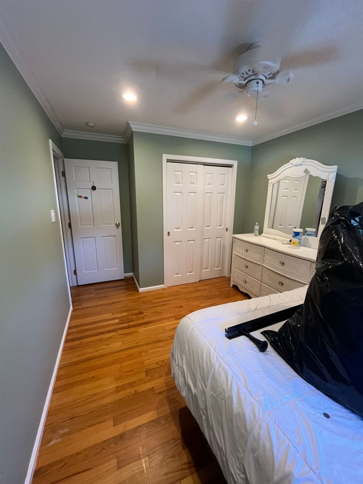 After: bedroom repainted sage green with crisp white trim and doors