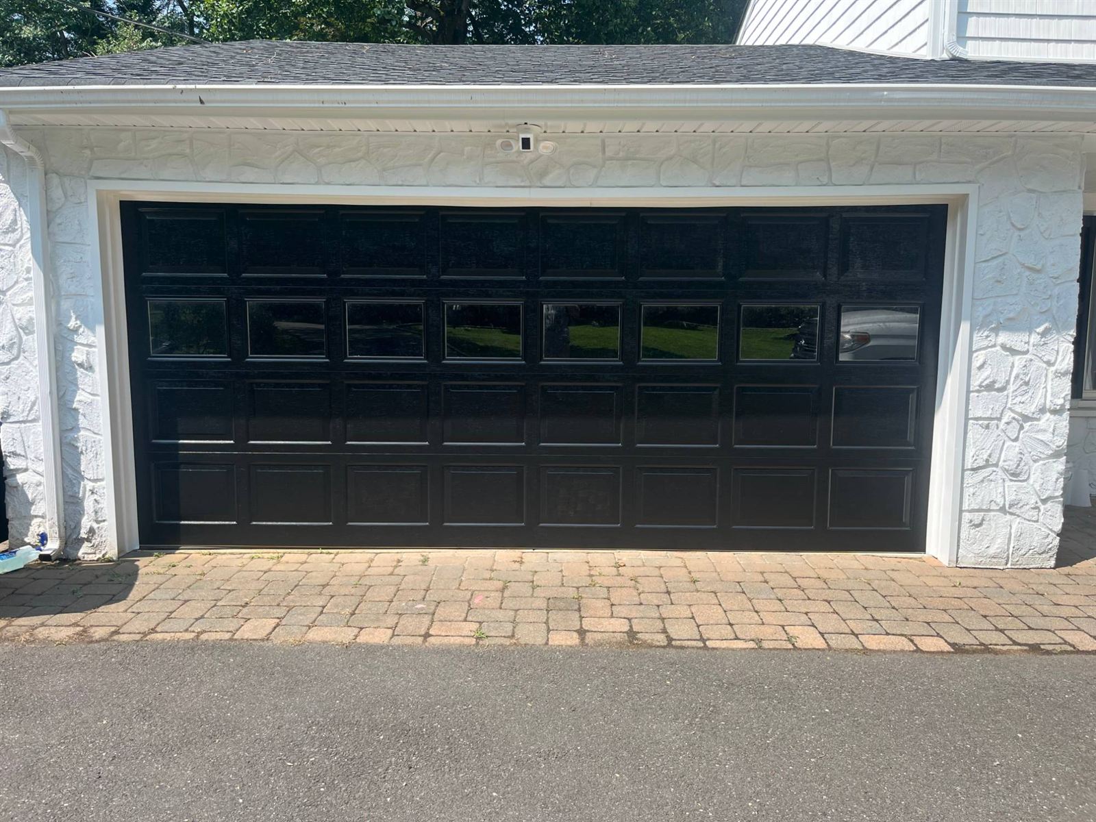 After: glossy black garage door with windows on a white stone garage