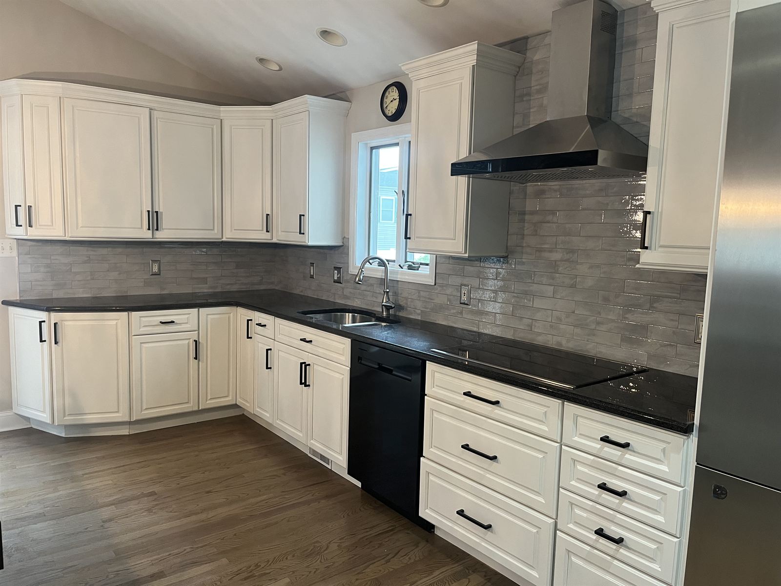 After: clean light gray subway tile backsplash under white cabinets and stainless hood